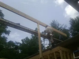 Carpenter setting a ridge beam over a new addition frame — Ice Dam Removal by Roofing Brothers in Lapeer