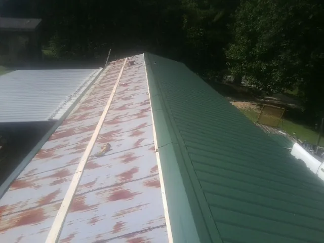 Old rusted panels beside newly installed green metal roofing — Wind Damage Roof Repair by Roofing Brothers in Lapeer