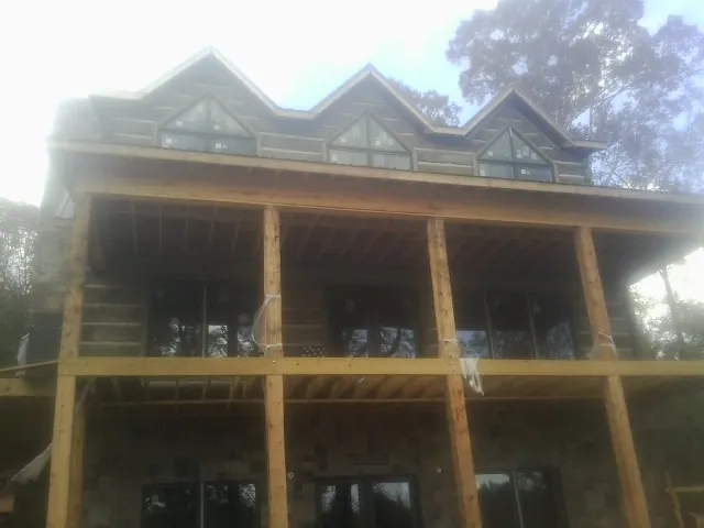 Dormers and porch framing on a large log home under construction — Roof Coating work by our crew in Lapeer