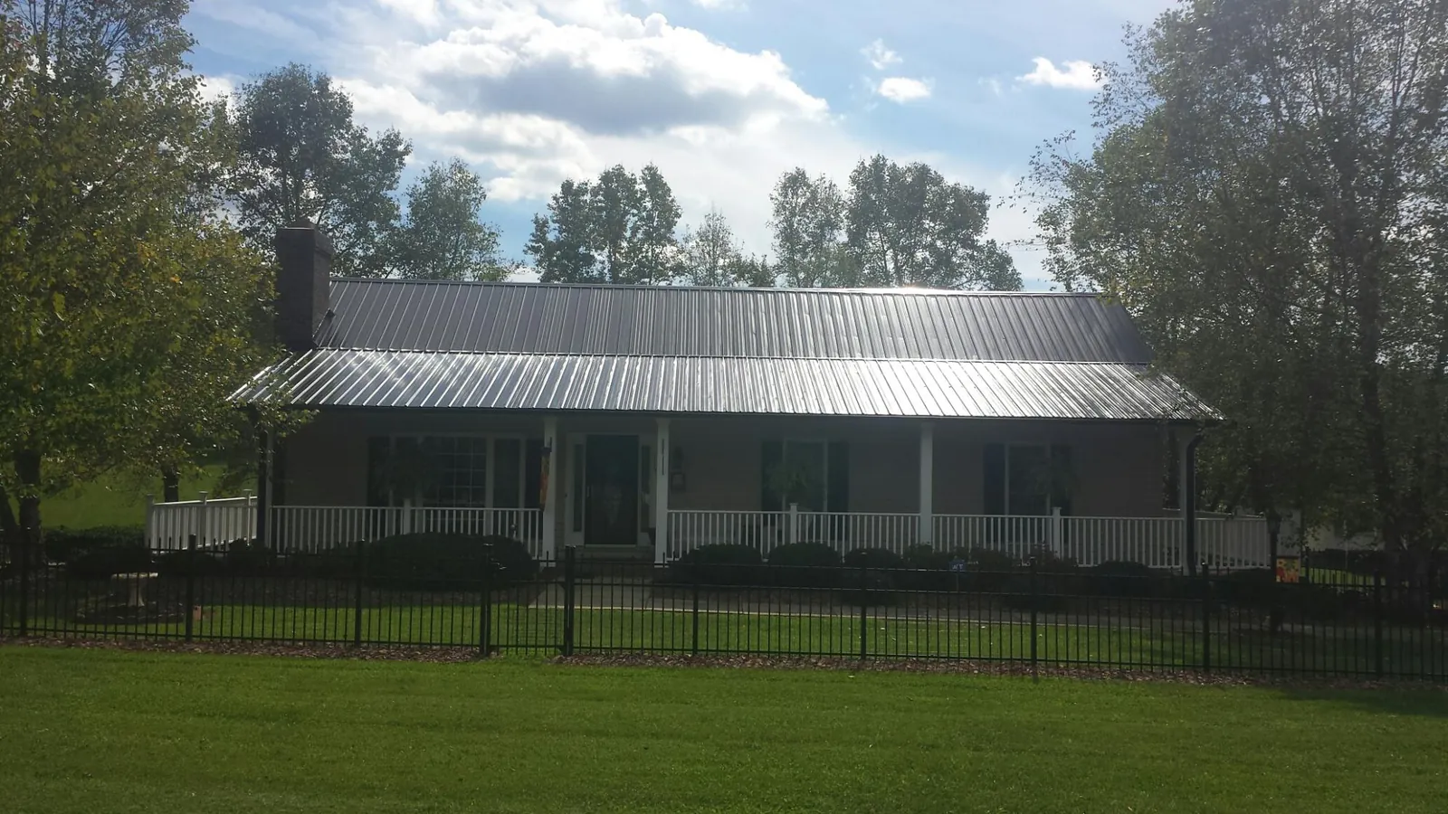 Gray metal roof on a brick ranch with a full width front porch — Gutter Guard Installation work by our crew in Lapeer