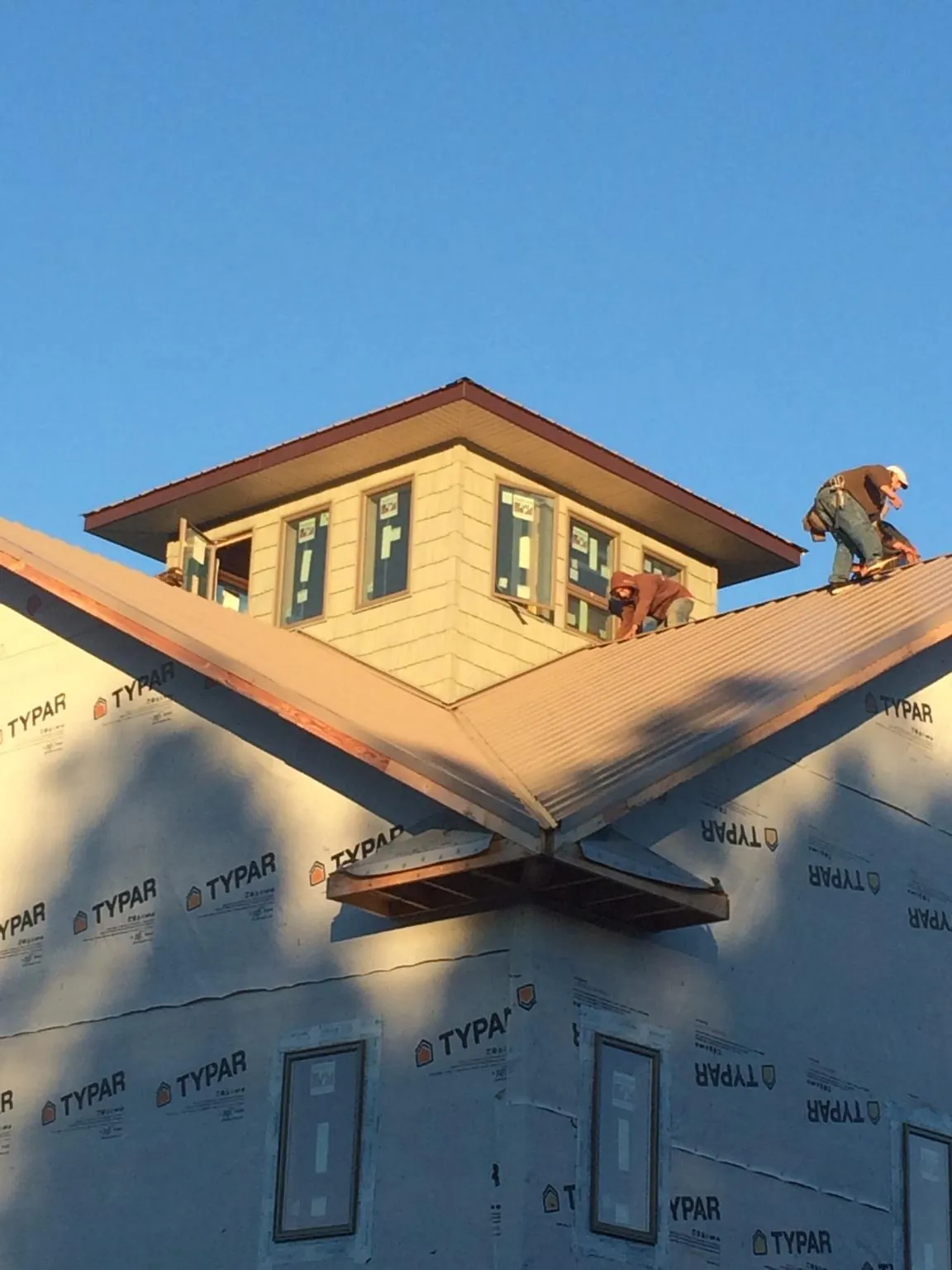Roofers working around a rooftop cupola on a new metal roof at sunset — Roof Waterproofing in Lapeer by Roofing Brothers